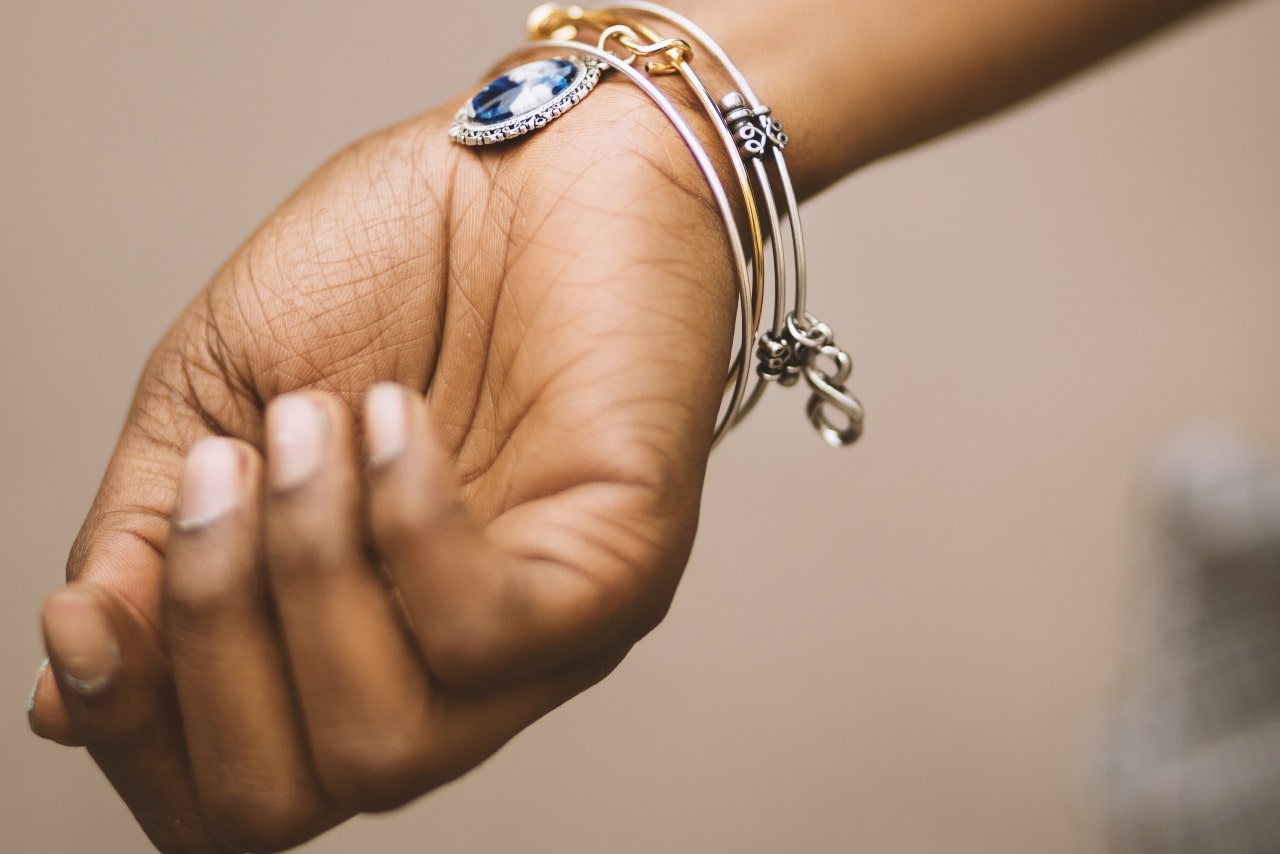A woman with four bracelets with different charms on the bangles stacked on her wrist