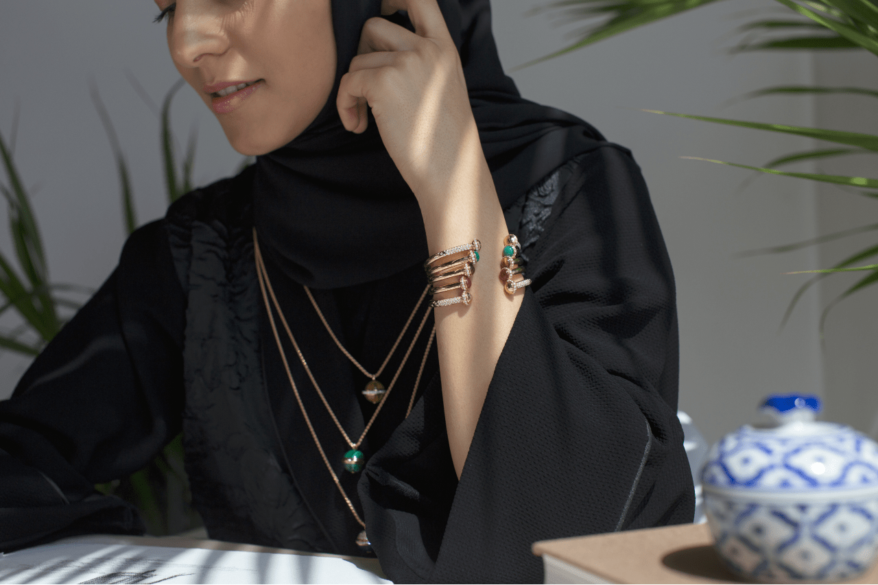 A woman wearing a black hijab and layered necklaces and bracelets