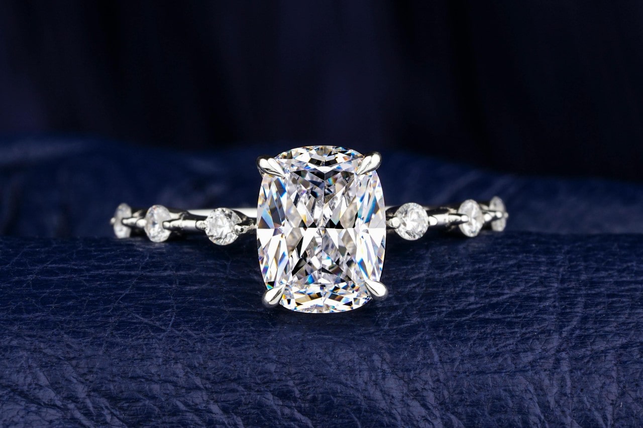 A close-up of a diamond engagement ring with a large center stone and spaced side stones.