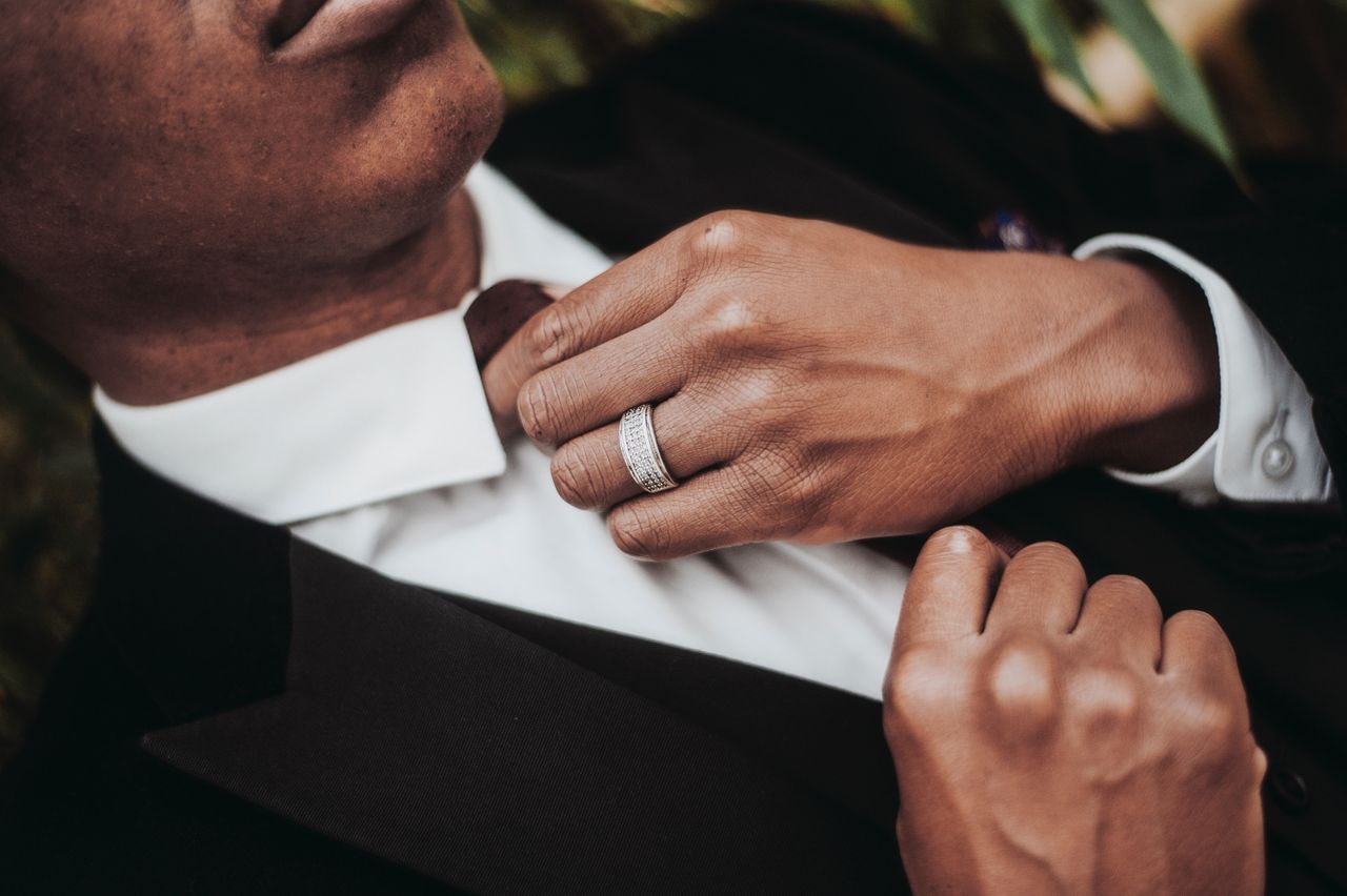 A close-up of a well-dressed man, with emphasis on his stunning wedding band.