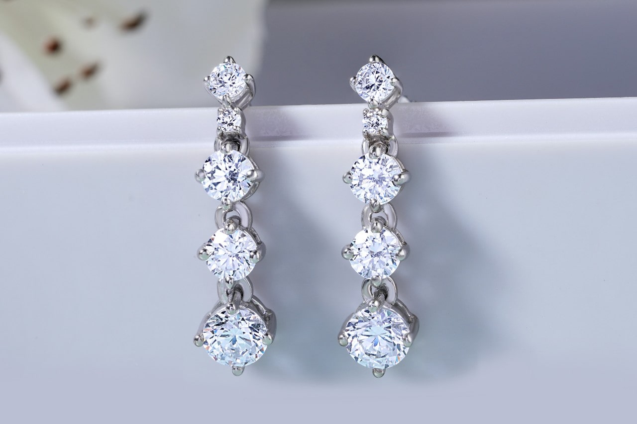 A pair of diamond drop earrings with four round cut diamonds increasing in size.