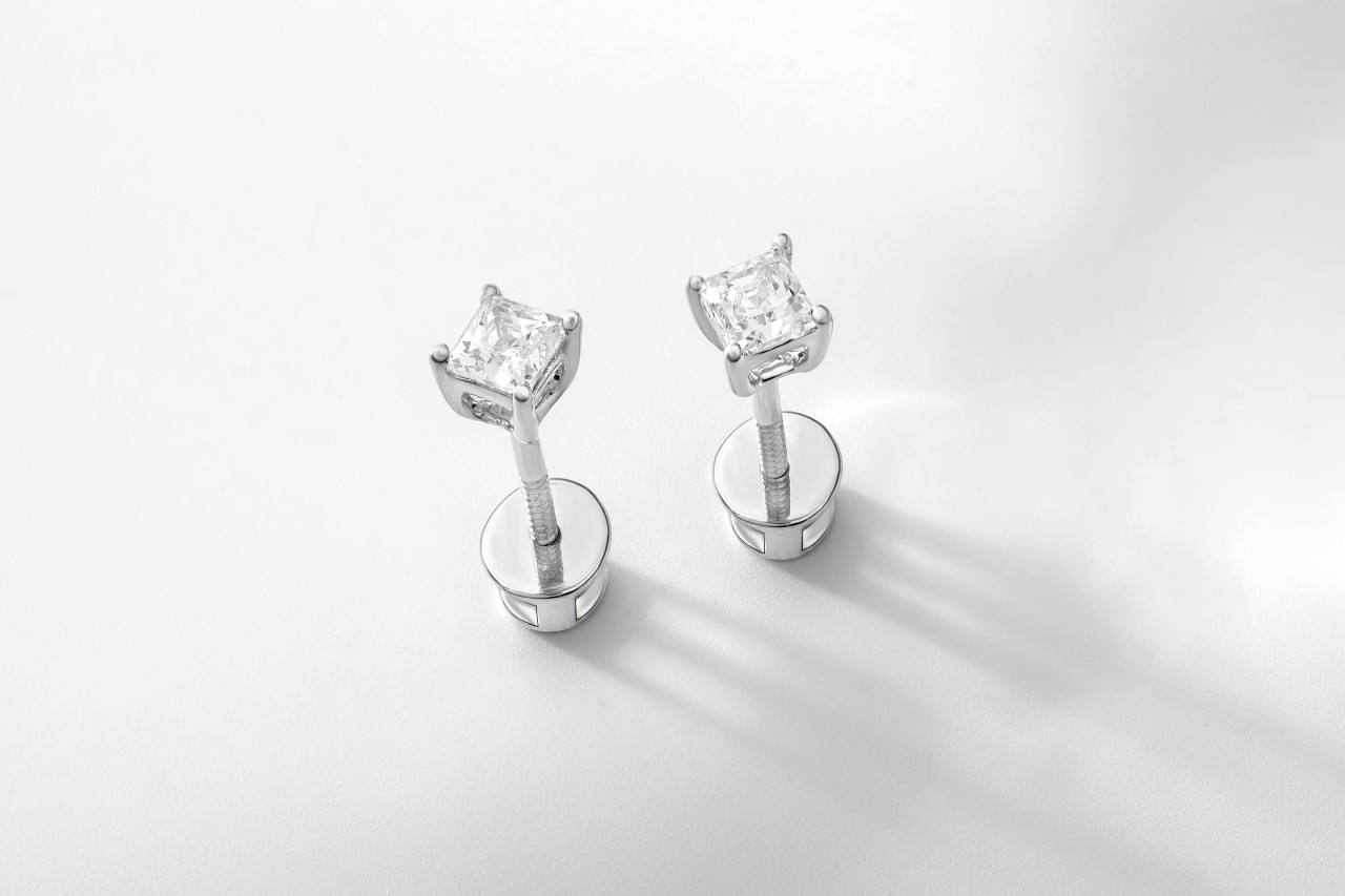 A pair of white gold diamond stud earrings on a white surface.