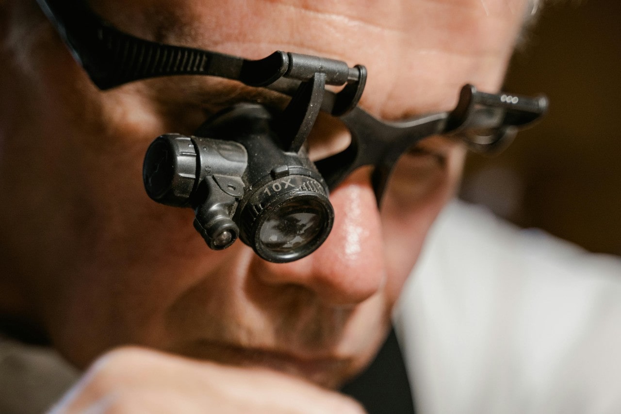 A jeweler with magnifying glasses inspecting something A jeweler with magnifying glasses inspecting something