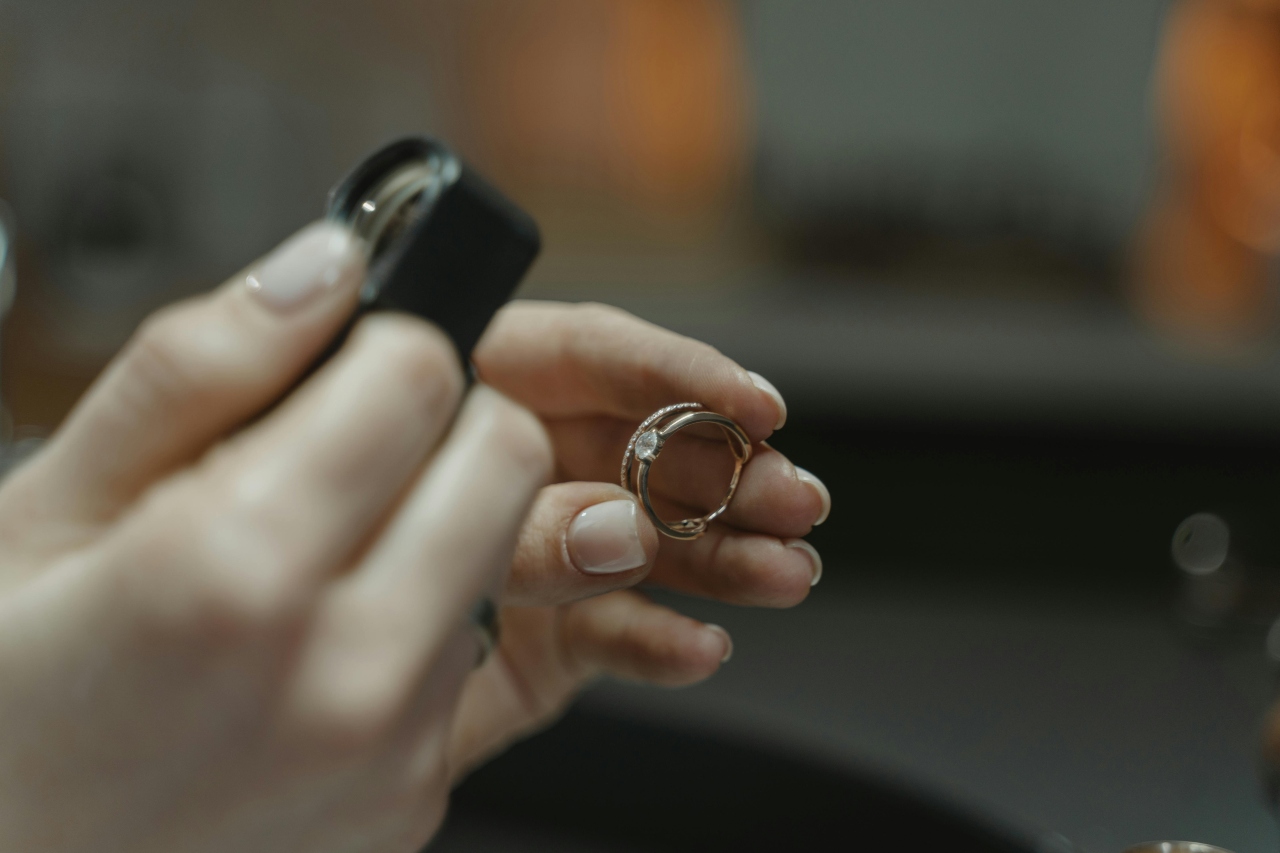 A hand holding a magnifying loop pointed at yellow gold diamond wedding set A hand holding a magnifying loop pointed at yellow gold diamond wedding set