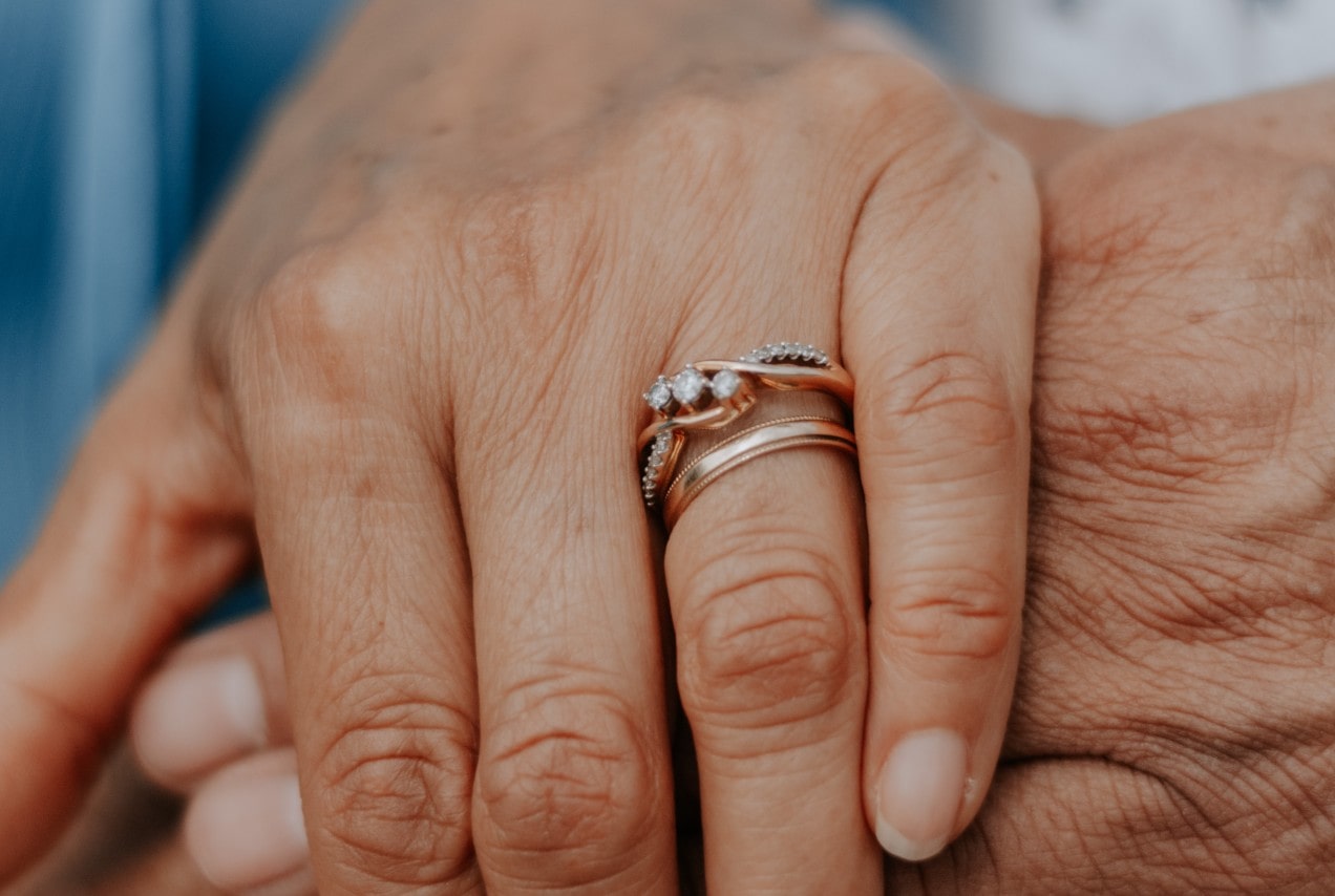 A close-up of a married couple’s hands, the bride wearing a matching wedding band set.