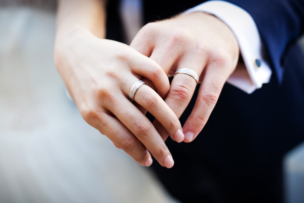 A close-up of a bride and groom’s hands, with emphasis on their matching wedding bands.