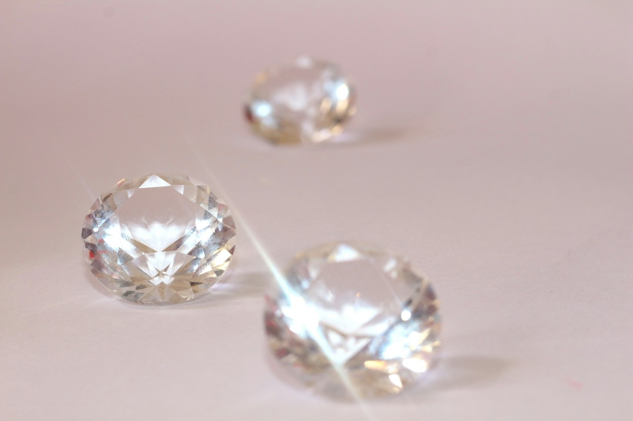 Three stunning round cut diamonds on a pink background.